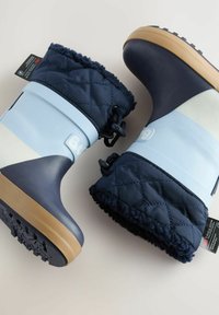 Botas impermeables en azul y marino con caña de tela acolchada, suela de goma y cordón ajustable; textura antideslizante en la suela para mayor tracción.