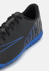 Černé a modré sportovní boty Nike s tkaničkami, texturovaným svrškem a modrou podrážkou, navržené pro venkovní sporty nebo každodenní nošení.