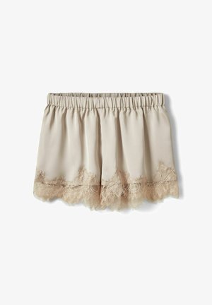 Beežide satiinist lühikesed püksid elastse vöökohaga ja sakilise pitsiservaga ääres, mille taust on valge.