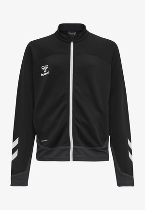 Giacca nera con zip e logo bianchi, polsini testurizzati e inserti in rete. Presenta righe a zig-zag bianche sulle maniche e un collo alto.