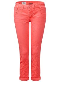 Jeans de color coral con un corte ajustado, diseño de cinco bolsillos, puños enrollados y detalles sutiles de textura. Cintura cosida y cierre de cremallera.