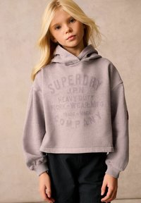 Felpa corta grigia chiara con una stampa frontale che recita "SUPERDRY COMPANY." Presenta un cappuccio e polsini a coste, abbinata a pantaloni corti scuri.