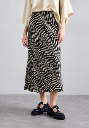 Black and beige zebra-striped midi skirt made of smooth fabric, featuring a wavy pattern, paired with chunky black shoes with blue accents.