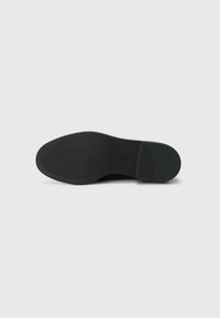 Zwarte rubberen schoenenbodem met een gladde, afgeronde vorm, met horizontale en verticale ribbels voor grip. Schone, minimalistische uitstraling.