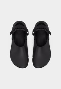 Ζευγάρι μαύρα ανατομικά παπούτσια χωρίς κορδόνια με ρυθμιζόμενους υφασμάτινους ιμάντες, στρογγυλές μύτες και οπές αερισμού κατά μήκος των πλευρών, σε θέα από πάνω.