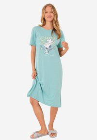 Un vestito da notte in cotone azzurro chiaro con maniche corte presenta una stampa grafica di Snoopy nei panni di un cuoco. Ha una vestibilità comoda e fessure laterali.
