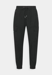 Zwarte cargobroek met elastische tailleband, vetersluiting en twee zijzakken. Heeft taps toelopende pijpen en contrasterende stiksel details.