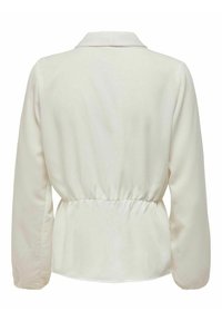 Blouse blanche à manches longues, avec un col et une taille élastique froncée. Texture lisse, matériau léger et design simple sans motifs visibles.