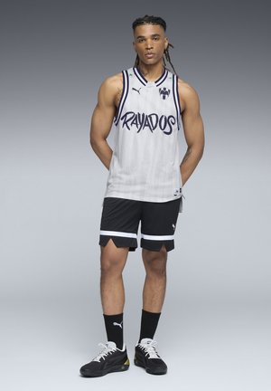 Hvid mesh basketballtrøje med "RAYADOS" tekst i blå, sammen med sorte shorts med hvide striber og sneakers.