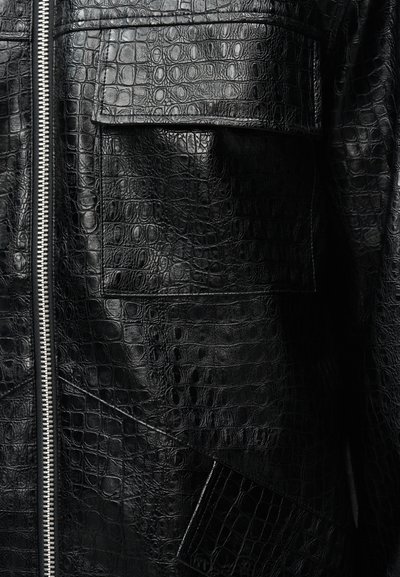 Μαύρο δερμάτινο μπουφάν από ψεύτικο δέρμα κροκοδείλου με ασημένιο φερμουάρ και τσέπες με καπάκι.