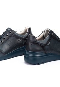 Zapatillas negras de cuero con un acabado texturizado, que presentan cordones redondos, un cuello acolchado y una suela de goma gruesa y duradera.