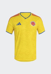 Maillot de football jaune avec bordures bleu et rouge, logo de l’équipe nationale de Colombie sur la poitrine et logo Adidas sur le côté droit.