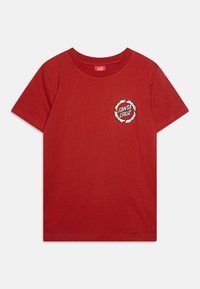 Sarkana kokvilnas T-kreklā ar īsām piedurknēm un apļa izgriezumu. Uz krūtīm ir apļa logo ar uzrakstu "Santa Cruz" melnā un baltā krāsā.