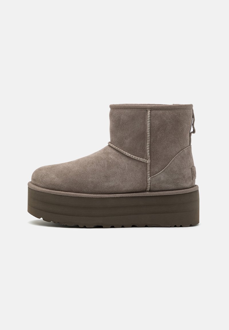 Bottine courte en daim taupe avec semelle plateforme épaisse marron foncé et détails de panneaux cousus, vue de côté sur fond blanc.