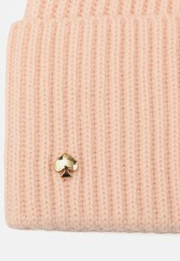 Ljust rosa stickad mössa med ribbad textur och ett guldhjärtsemblem på framsidan. Mjuk och ull-liknande material för värme.