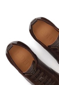 Καφέ δερμάτινα παπούτσια με σουέντ λεπτομέρειες, στρογγυλεμένο σχήμα και κορδόνια. Το εσωτερικό διαθέτει ανάγλυφη επωνυμία και λεία υφή δέρματος.