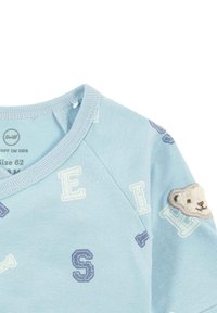 Světle modrý bavlněný top s kulatým výstřihem, s texturovanými písmeny a detailní aplikací medvídka na rameni. Velikost 62.