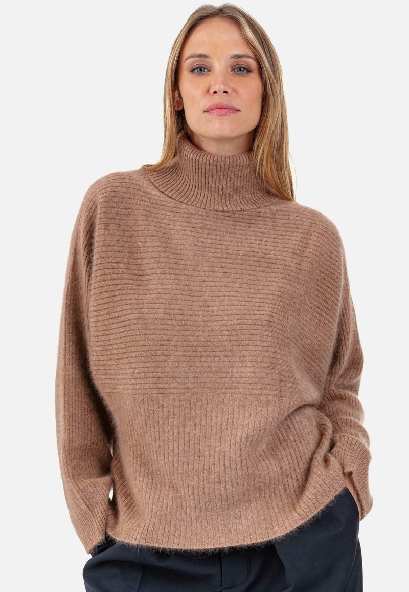 Pull à col roulé côtelé marron avec une coupe ample, une texture douce et un ourlet légèrement plus court, présentant des manches longues et une silhouette décontractée.