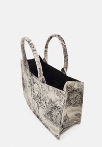 Plátěná taška přes rameno s černobílým vzorem krajiny, vybavená dvěma kulatými uchy a otevřeným vrškem, s texturovaným povrchem.