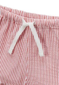 Tissu rayé rouge et blanc avec une apparence texturée, doté d'un cordon blanc et d'une taille élastique froncée.