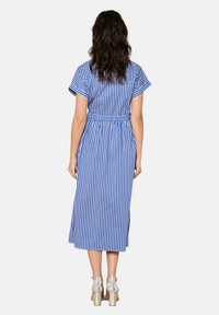 Vestito midi a righe blu con maniche corte, vita stretta e spacchi laterali, abbinato a sandali metallici con tacco a blocco.