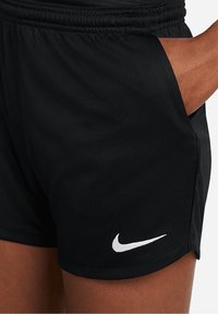 Pantalones cortos deportivos negros hechos de tejido ligero con cintura elástica. Presentan un bolsillo lateral y un logo de Nike en blanco en el dobladillo.