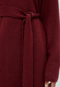 Burgunderfarbener Strickcardigan mit langen Ärmeln, ausgestattet mit einem gebundenen Taillengürtel und gerippten Bündchen, strukturiertem Stoff und mittlerer Dicke.