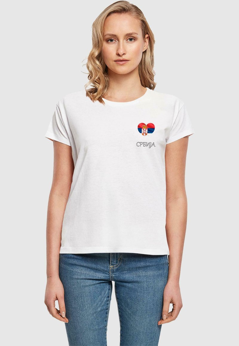 Hvit bomull T-skjorte med korte ermer, med et hjerte-design i rødt, blått og en krone, med ordet "Србија" i grått under.