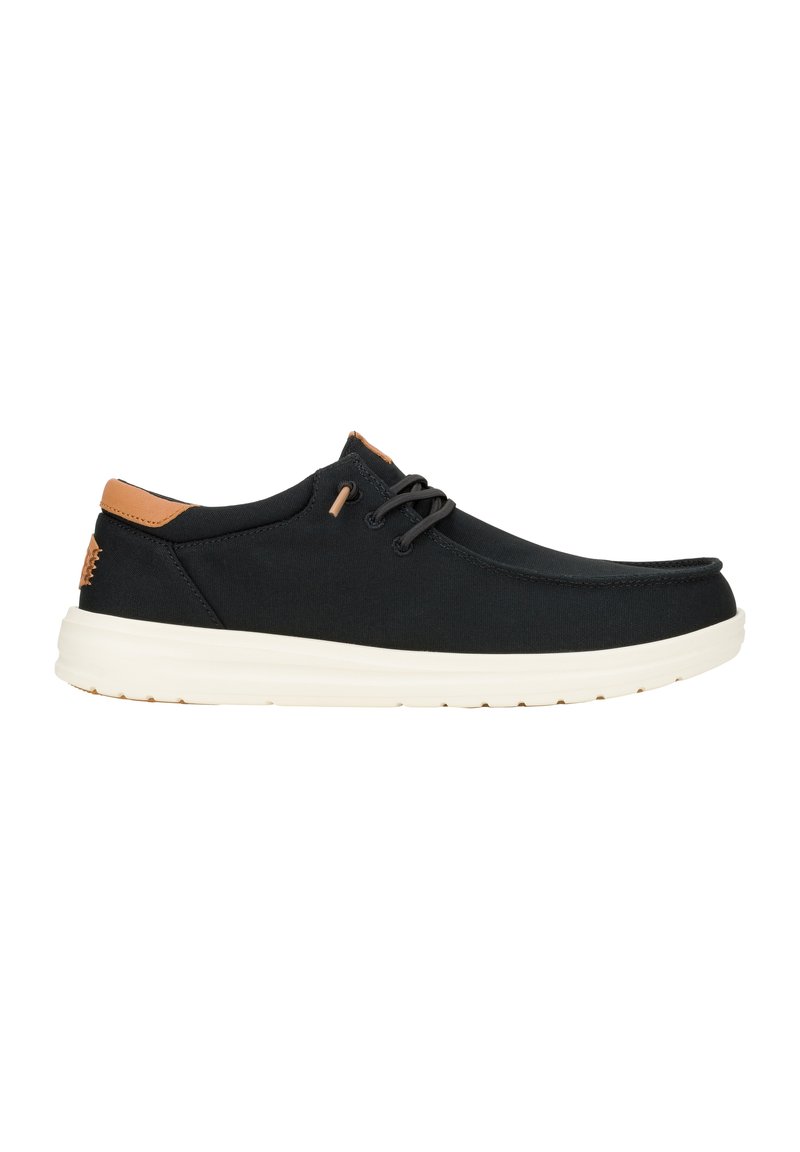 Scarpe in tessuto nero con un design della punta arrotondata, dettagli in pelle beige sul tallone e suola bianca imbottita. Presentano lacci e occhielli neri.