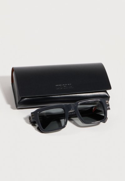 Lunettes de soleil rectangulaires noires avec verres foncés reposant devant un étui en cuir noir élégant embossé d'un logo.