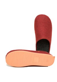 Red wool clogs with a flexible orange rubber sole. Features a closed back and a textured interior for comfort. Simple design with minimal hardware.
