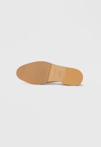 Sole di una scarpa da dress in pelle marrone chiaro con punta texture, tacco liscio, e marchi del brand e della taglia stampati al centro.