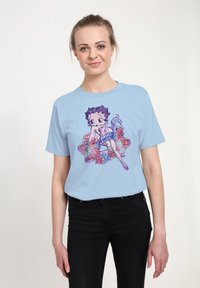 Ljusblå t-shirt med en tryckt illustration av en tecknad figur omgiven av färgglada rosor. Korta ärmar och standardpassform.