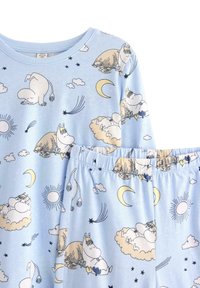 Lysblå bomulds pyjamas sæt med tegneseriefigurer, halvmåner og skyer. Overdelen har en rund halsudskæring; bukserne har en elastisk talje.
