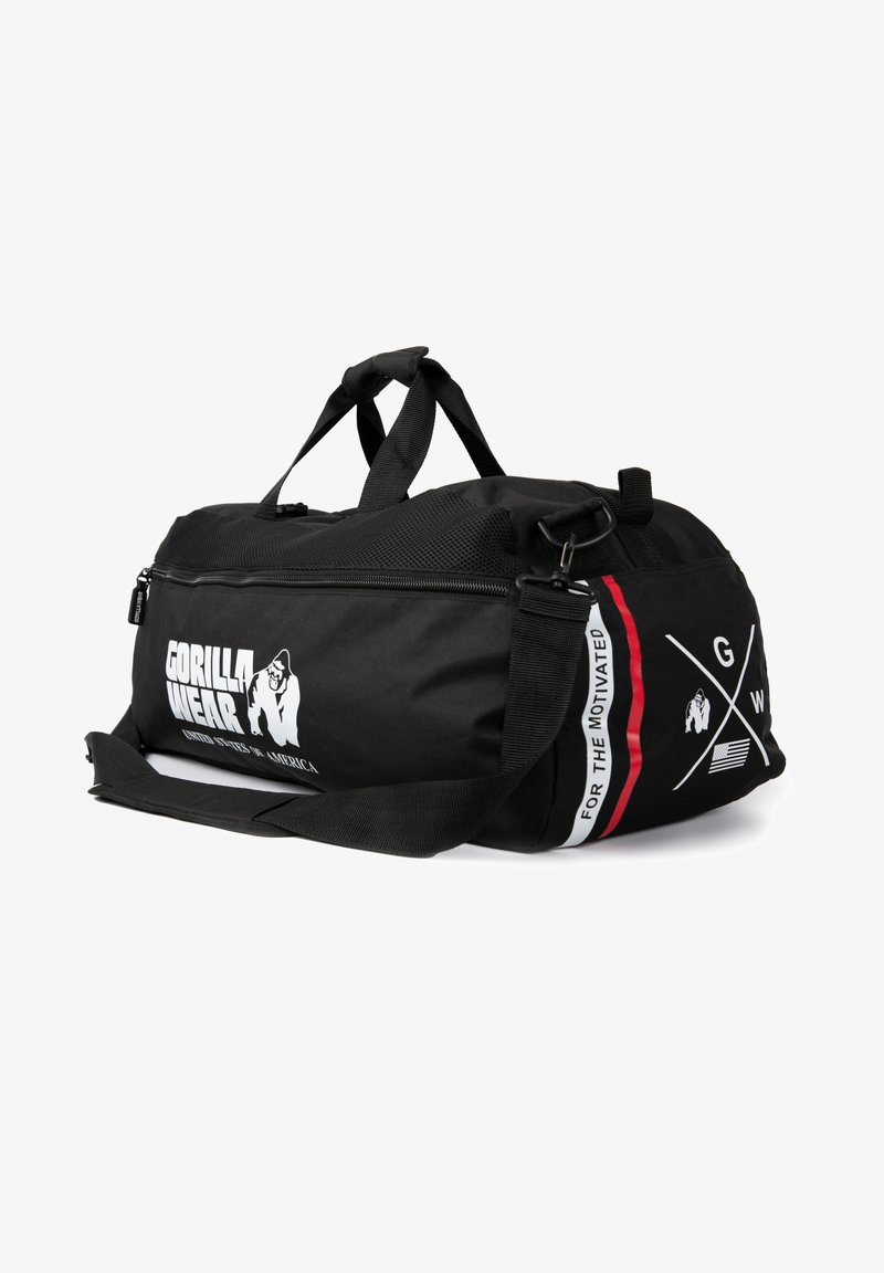 Svart träningsoverallväska i slitstarkt tyg, med dragkedjestängning, dubbla handtag och en avtagbar axelrem med logotyp och detaljer.