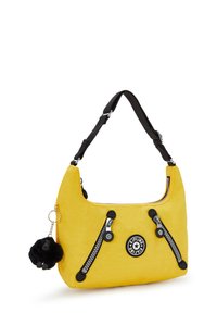 Bolso de nylon amarillo con acentos negros, cuenta con dos bolsillos con cremallera, un logo circular y un charm de pelaje negro adherido a la correa.