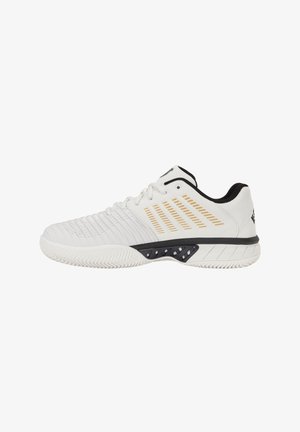 Chaussure de sport blanche avec des accents noirs et dorés, semelle texturée, laçage à l’avant et col matelassé pour le soutien et le confort.