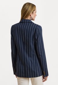 Laivaston sininen pinstripe bleiseri, jossa on muotoiltu istuvuus, hahlot ja kolmen napin hihansuu yksityiskohtia, valmistettu teksturoidusta kankaasta.