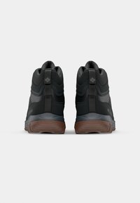 Czarne wysokie buty górskie z teksturowaną cholewką, wzmocnionym piętą i gumową podeszwą. Posiadają szczegóły logo oraz pętle ułatwiające zakładanie.