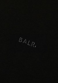 Svart tyg med präglade bokstäver "BALR." i en kontrasterande ljus nyans. Texturen verkar jämn utan synliga mönster eller utsmyckningar.
