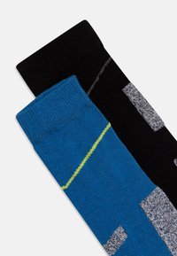 Due paia di calzini: uno blu con una striscia gialla, l'altro nero con motivi geometrici grigi e bianchi. Tessuto lavorato a maglia, lunghezza fino al polpaccio.
