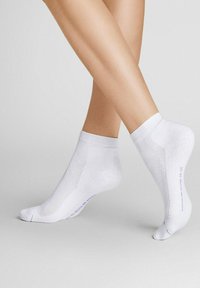 Weiße Knöchelsocken mit glatter Textur, verstärktem Fersen- und Zehenbereich und dezentem lila Branding an der Unterseite.