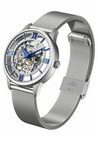 Montre automatique argentée avec un cadran transparent, des chiffres romains bleus, des aiguilles bleues, et un bracelet en acier inoxydable maillé. Cristal saphir remarquable.