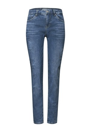 Jeans de denim azul con corte slim, que presentan parches desgastados, diseño de cinco bolsillos, cremallera y detalles de costura visibles.