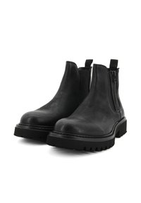 Stivaletti neri in pelle con suola in gomma bassa e spessa, chiusura con zip e linguette sul retro per una facile indossatura. Texture liscia.