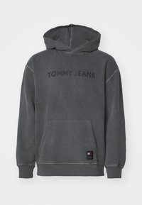 Harmaa huppari, valmistettu pehmeästä puuvillasta, jossa edessä kirjailtu "TOMMY JEANS" -teksti, kengurutasku sekä resorit hihansuissa ja helmassa.