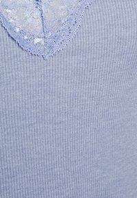 Light blue ribbed top featuring a lace V-neckline. The fabric has a soft texture with subtle sheen, providing a delicate contrast at the collar.