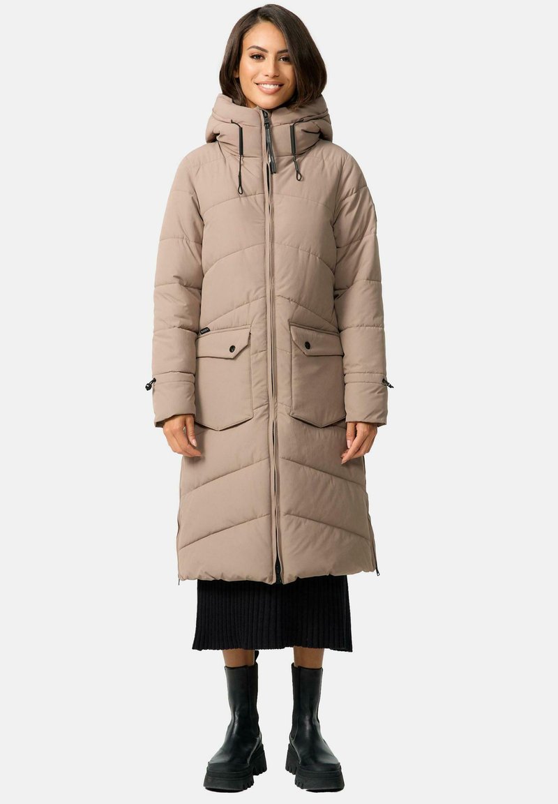 Beige padded coat with a hood, featuring two front pockets, zip closure, and chevron quilted pattern. Styled with a ribbed black skirt and boots.