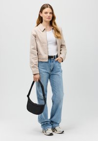 Giacca cropped beige, canotta bianca, jeans blu a vita alta, borsa nera e sneaker chiare. Design semplice con una vestibilità comoda.