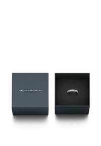 Bague en argent présentée dans une boîte noire avec des lettres dorées. La bague possède un design texturé avec plusieurs petites pierres. La boîte est bleu marine.
